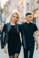 Elegant couple in black clothes walking the street holding hands