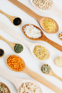 mixed pulses in wooden spoon. rice, red lentils, green lentils, corn, bulgur, dried mint, isot, black pepper, oregano, pasta, wire noodle, scallops.