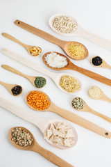 mixed pulses in wooden spoon. rice, red lentils, green lentils, corn, bulgur, dried mint, isot, black pepper, oregano, pasta, wire noodle, scallops.