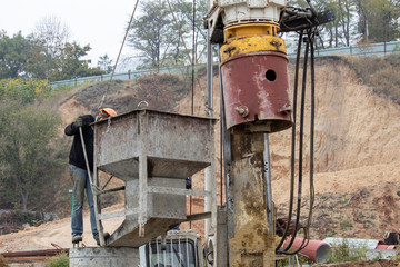 Worker drains concrete from container into foundation