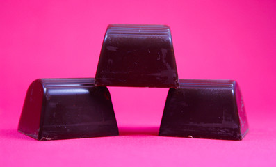 delicious dark chocolate bonbons on red background for dinner or snack
