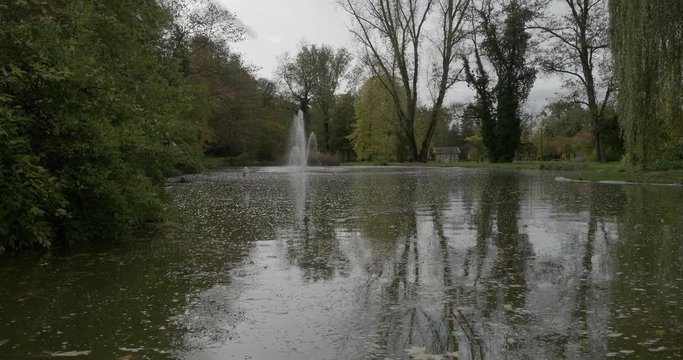 Kurpark von Bad Bellingen in S&uuml;dschwarzwald. Wasserstrahl mitten in einem kleinen Teich mit Eichen, Ahorn und Nadelb&auml;umen mit herbstfarben