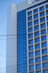 Obraz na płótnie Canvas Modern high-rise building with facade glazing built in a park area by the sea