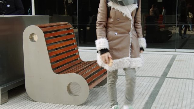 mujer sentada en un banco con el  telefono en la mano