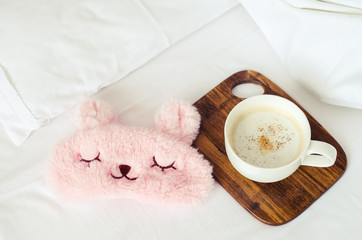 Cup of coffee with cute pink sleep mask