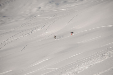 Man and woman riding down the hill on the snowboard