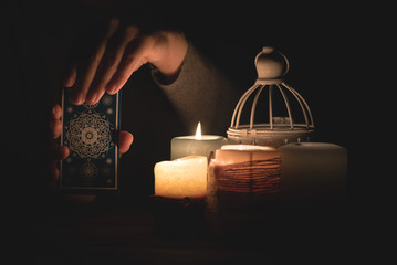 Fortune teller reading a future by tarot cards in the light of candle concept.