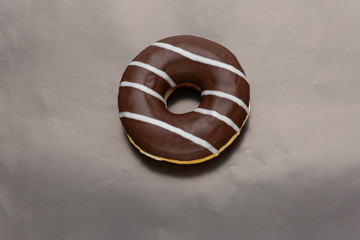 chocolate donut with white stripes on black background, top view