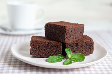 dark chocolate brownie pieces decorated with mint and berries on a white plate classical  recipe 