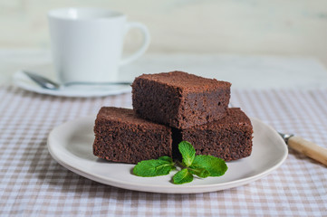 chocolate brownies cake decorated with mint and berries on a white plate