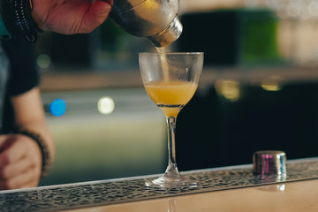 Bartender pouring cocktail at bar counter