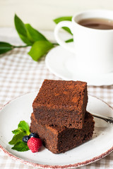 dark chocolate brownie pieces decorated with mint and berries on a white plate classical  recipe 