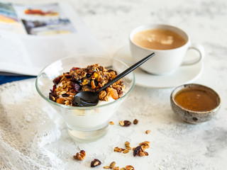Healthy breakfast. Granola, muesli with pumpkin seeds, honey, yogurt in a glass bowl with a cup of coffee on white background. Breakfast of a modern girl. Close up, copy space.