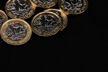 one pound coins in the left corner on the top against black background with copy space