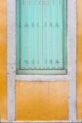 un volet bleu vert sur un mur jaune