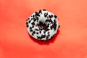 white donut dusted with cookies on red background, top view