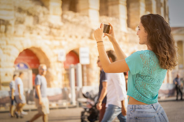 Girl tourist on vacation in Verona taking pictures, Italy, in front of the arena of Verona before...