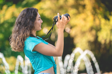 Smiling girl in an Italian city with a camera in her hand. Tourist or professional photographer.