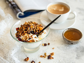 Healthy breakfast. Granola, muesli with pumpkin seeds, honey, yogurt in a glass bowl with a cup of coffee on white background. Breakfast of a modern girl. Close up, copy space.
