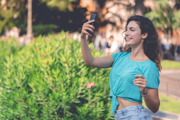 Smiling girl taking a selfie with herself behind of green plants