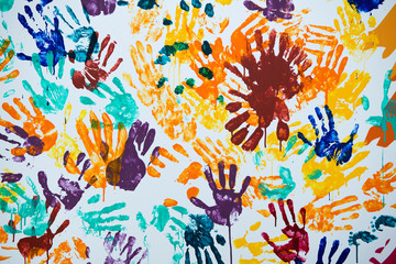 texture of multi-colored prints of hands smeared with paint on a white wall