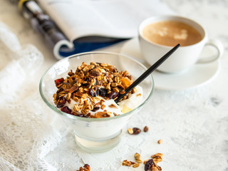 Healthy breakfast. Granola, muesli with pumpkin seeds, honey, yogurt in a glass bowl with a cup of coffee on white background. Breakfast of a modern girl. Close up, copy space.