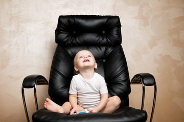 smiling child sitting in a large black office chair