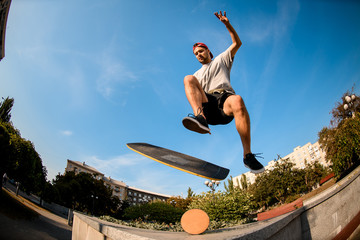 Fototapeta na wymiar Fish-eye shot boy jumping on the balance board on the concrete border in the park
