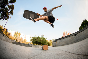 Fish-eye shot from below man making trick on the balance board on the concrete border