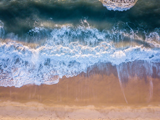 Drone picture of waves hitting the beach.