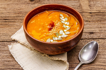 Autumn pumpkin cream soup. Traditional ingredients, healthy food concept. Napkin, vintage wooden background