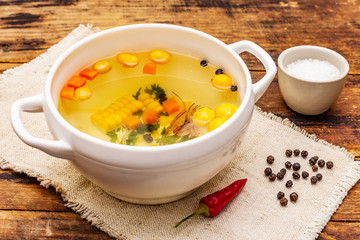 Transparent duck broth with dumplings and vegetables. Traditional bouillon, healthy food. Old wood background