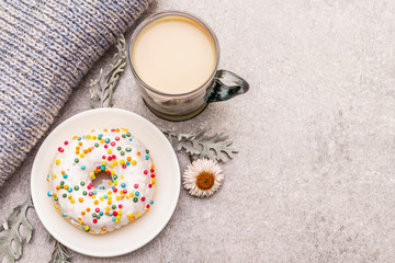 Hot coffee with a donut. Winter drink for a good mood with sweater, leaves and flowers. Old wood...