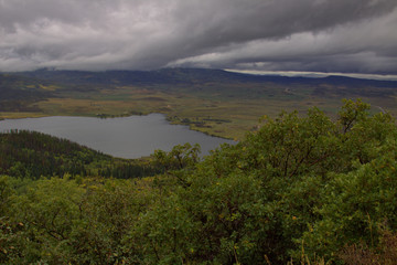 Fototapeta na wymiar Storm clouds forming coming across the mountain range in early fall with a lake in the foreground