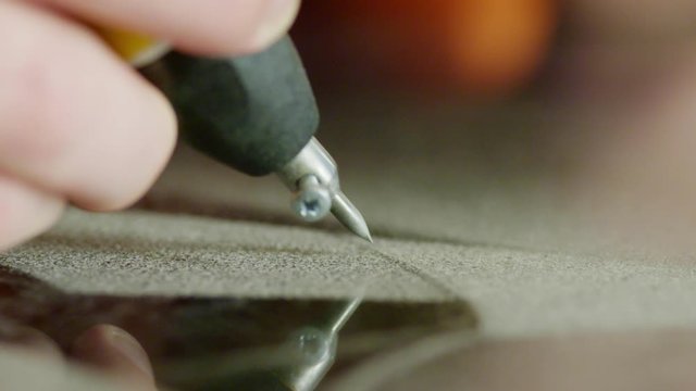 Closeup view of worker's hand is carefully sandblasting writing as kind of engraving on dark surface of granite block dedicated for memorial stone, headstone or grave marker.
