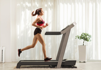 Young woman running on a treadmill at home