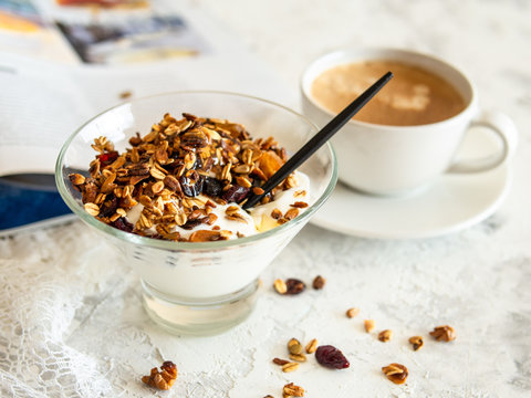 Healthy breakfast. Granola, muesli with pumpkin seeds, honey, yogurt in a glass bowl with a cup of coffee on white background. Breakfast of a modern girl. Close up, copy space.
