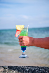 Woman holding cocktail on the beach overlooking ocean in Fiji