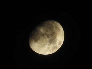 a bright three-quarter moon stands in the night sky