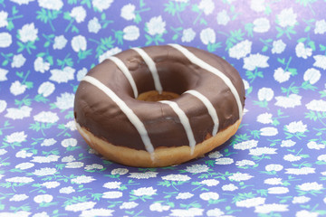 donut on purple with white flowers background, close up view