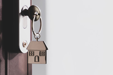 The home key with house keyring in the door keyhole with copy space. The concept of renting or selling a house or flat, mortgage and real estate, property buying