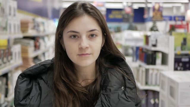 In the mall supermarket: a young woman in a black jacket goes shopping
