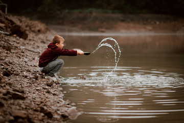 Boy Playing in Flooded Rain Water Cleaning Shell 