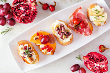 Assortment of crostini appetizers with a variety of toppings. Above view table scene on a bright background. Party food concept.