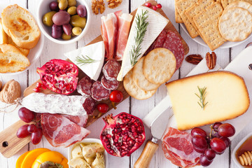 Charcuterie board of assorted cheeses, meats and appetizers. Top view table scene on a white wood...