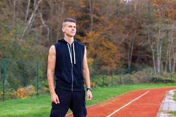 Portrait of a young man jogger in the morning outdoors standing on running race track