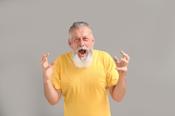 Angry mature man on grey background