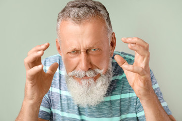Angry mature man on color background