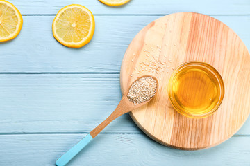Bowl with honey, lemon and spoon with sesame on wooden table