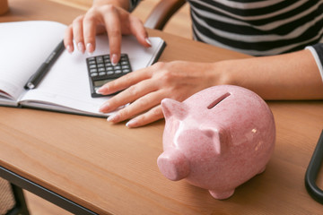 Piggy bank and woman counting money at table